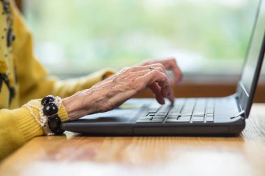 Laptop ve yaşlı kadının elleri.