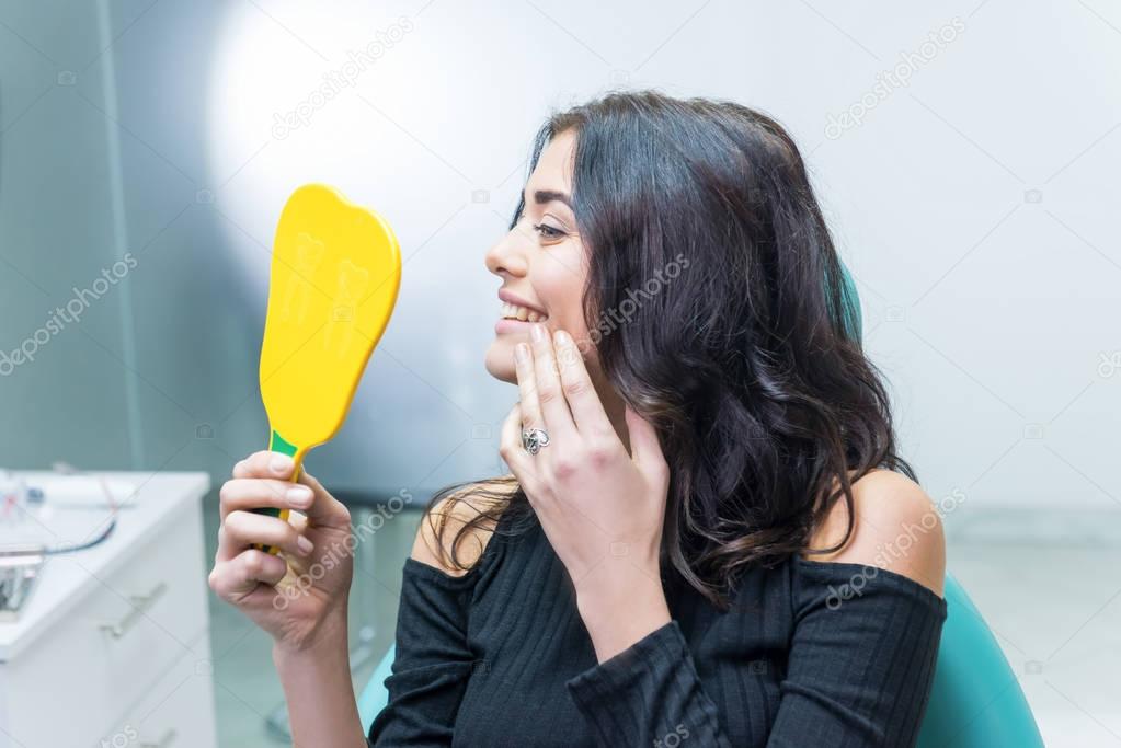 Female checking teeth in mirror.