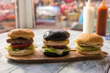 Ahşap tahta üzerinde üç hamburger.