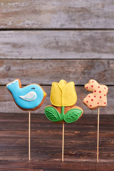 Cookies on sticks, wooden background.
