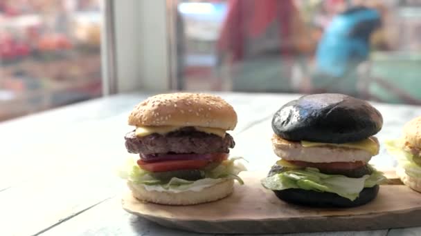 Tres hamburguesas y tablero de madera . — Vídeos de Stock