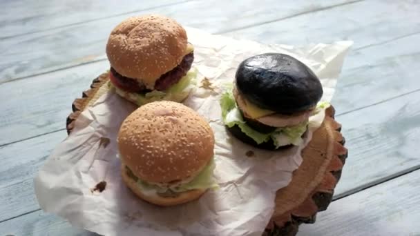 Drie hamburgers op houten achtergrond. — Stockvideo