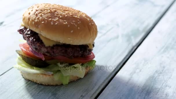 Burger σε γκρι ξύλινη επιφάνεια. — Αρχείο Βίντεο