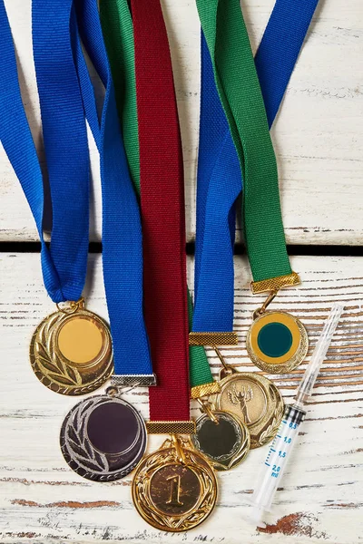 Syringe and medals on wood.