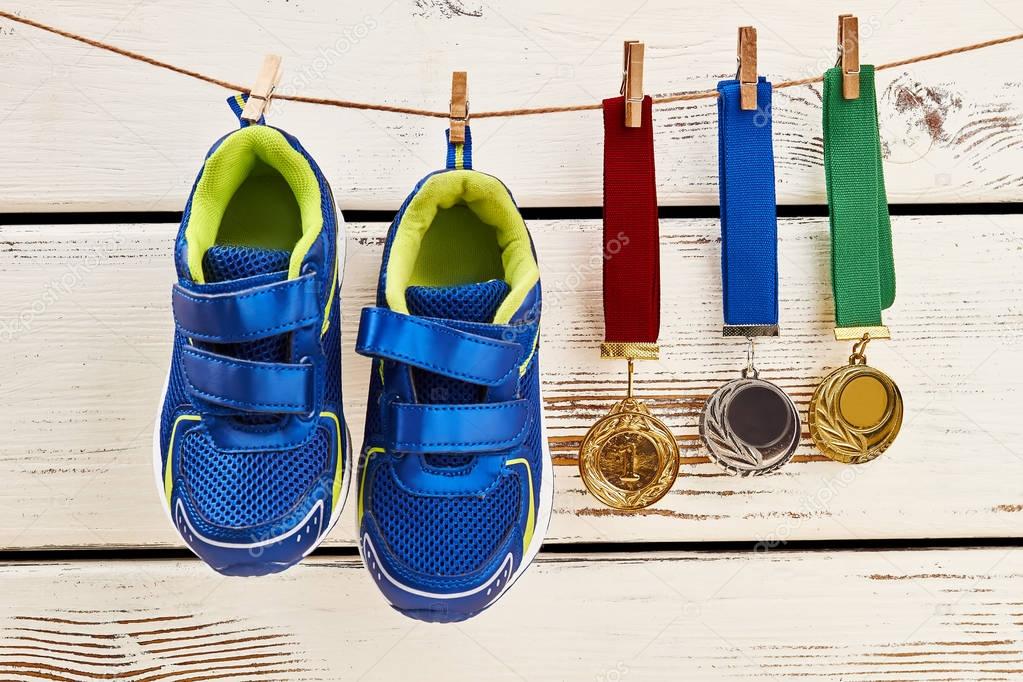 Sneakers and medals on clothesline.