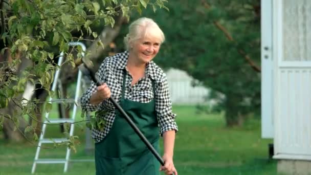 Äldre dam arbetar med rake. — Stockvideo