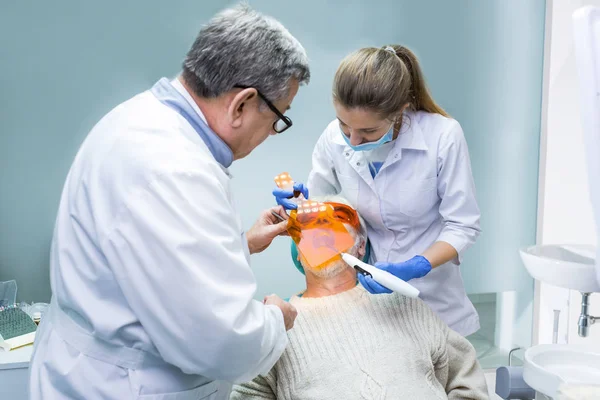 Tandläkare med hjälp av ultraviolett ljus. — Stockfoto