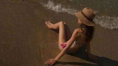 Kadın sahil üzerinde oturuyor.