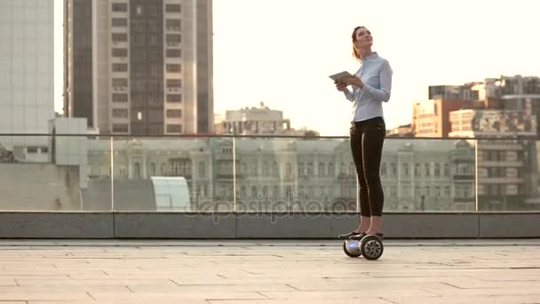 Vrouw op hoverboard, stedelijke achtergrond. — Stockvideo