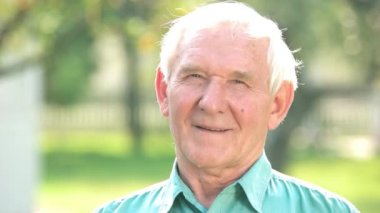 Elderly man smiling outdoors.