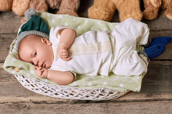 Infant in basket, wooden background.