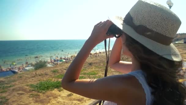 Vrouw op zoek naar een verrekijker, aan zee. — Stockvideo