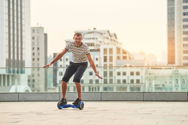 Guy paardrijden hoverboard, stad achtergrond. — Stockfoto