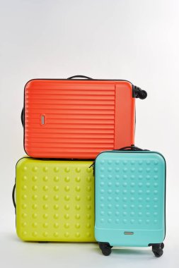 Üç renkli bavul, beyaz arka plan.