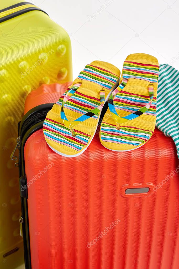 Colorful sandals on red suitcases.
