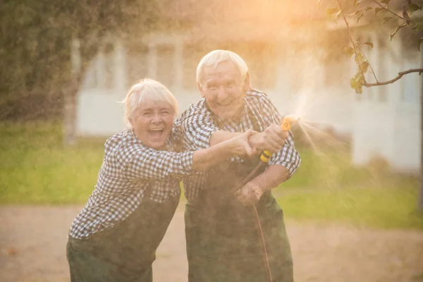 Altes Paar mit Gartenschlauch. — Stockfoto