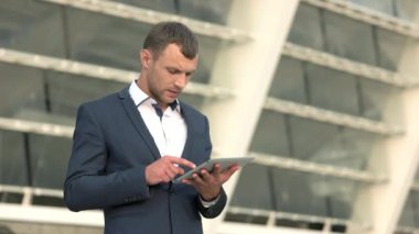 Bir tablet ile gülümseyen iş adamı.