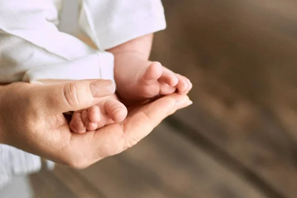 Female hand holding baby feet. — Stock Photo, Image