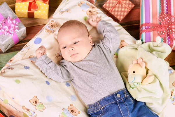 Little child and presents. Baby on pillow.