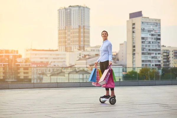 Mulher no hoverboard, sacos de compras . — Fotografia de Stock
