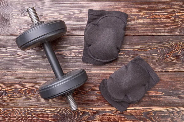 Dumbbell, elbow pads, wooden floor.