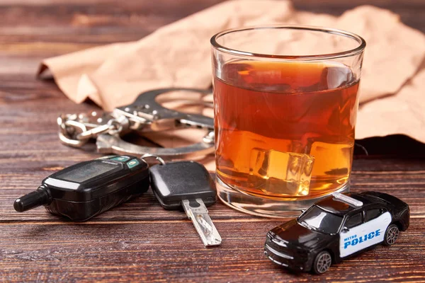 Whiskey, kulcsok, bilincs, rendőrségi autó. — Stock Fotó