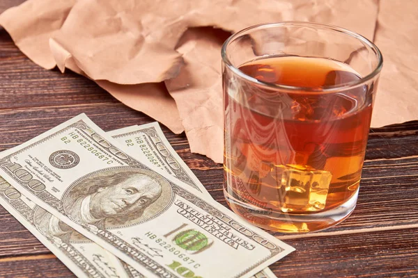Dolarů, sklenice whiskey, papírové, dřevěné pozadí. — Stock fotografie