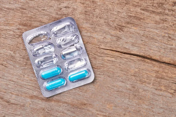 Blister with pills, wooden background.
