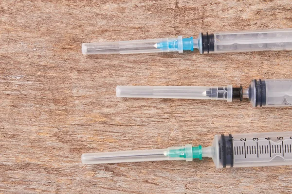 Injection needle syringes, wooden background.