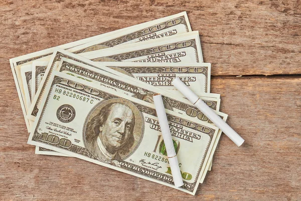 Cigarety, ležící na americký peníze. — Stock fotografie