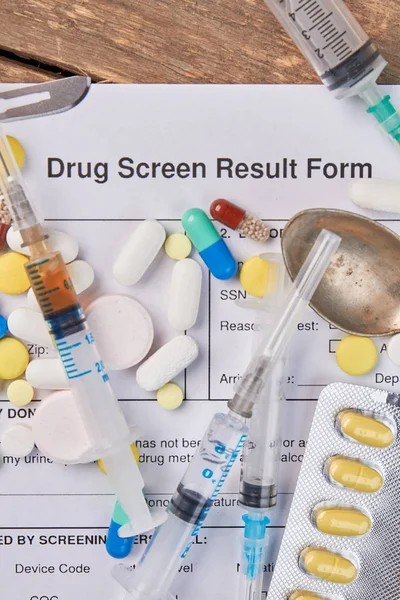 Drug screen result form, pills, syringes.