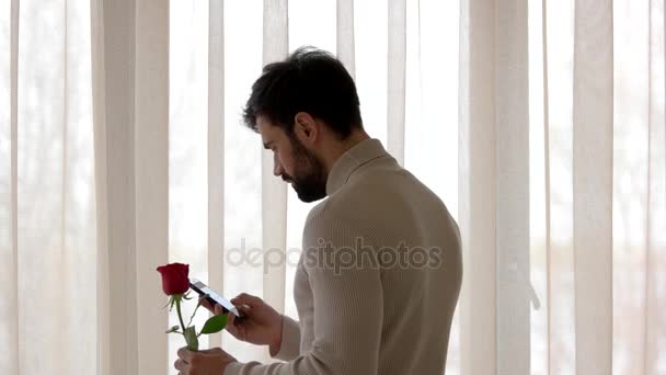 Hombre sosteniendo flor y teléfono . — Vídeo de stock