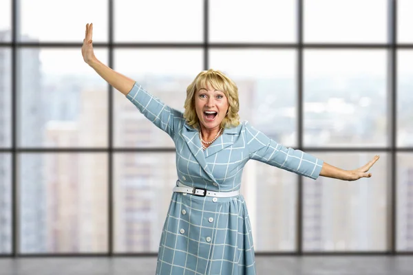 Laughing mature woman on office window background.