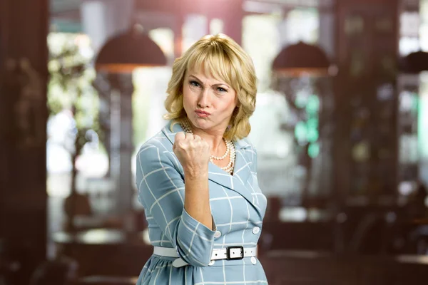 Aggressive mature woman putting up fist.