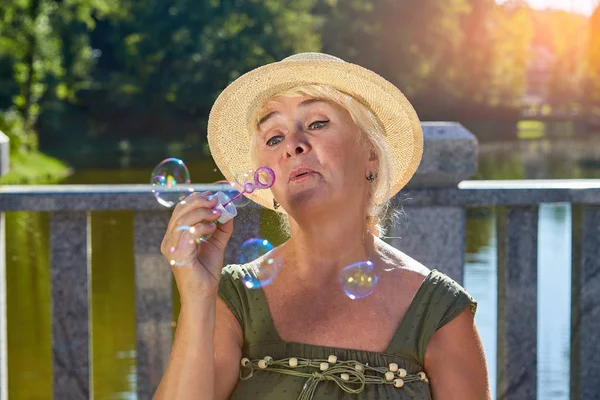 Mujer mayor soplando burbujas de jabón . — Foto de Stock