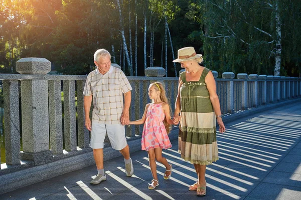 Child and grandparents holding hands.