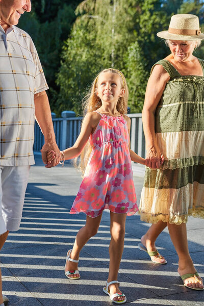 Внук, бабушка и дедушка держатся за руки
.