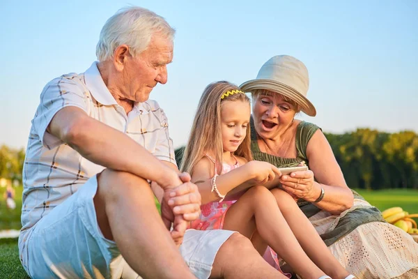 Kız holding tablet, büyükanne ve büyükbaba. — Stok fotoğraf