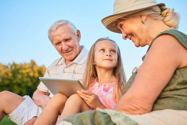 Niño con una tableta, abuelos . — Foto de Stock