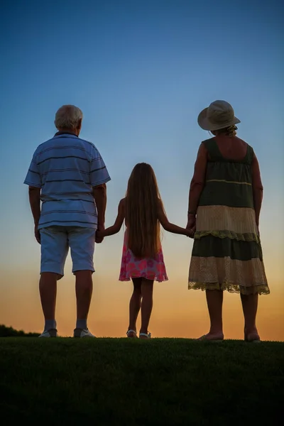 Дівчина з дідусем і бабусею, небо заходу сонця . — стокове фото