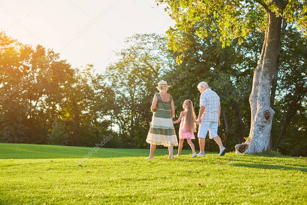 Grandparents and grandchild walking outdoors.