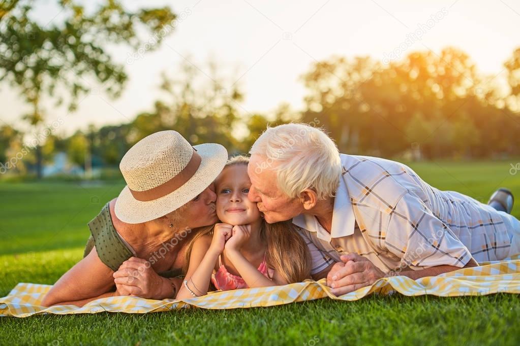 Grandparents kissing granddauther.