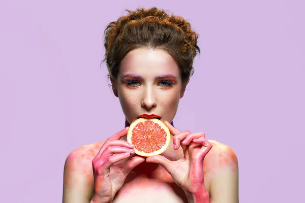 Beautiful girl biting grapefruit slice. — Stock Photo, Image