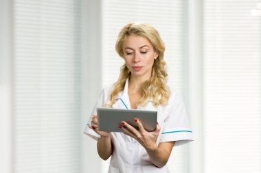 Genç hemşire bilgisayar tablet üzerinde çalışan.