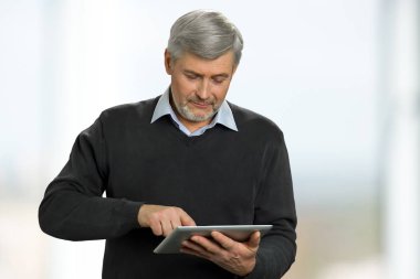 Dijital tablet üzerinde çalışan olgun adam.