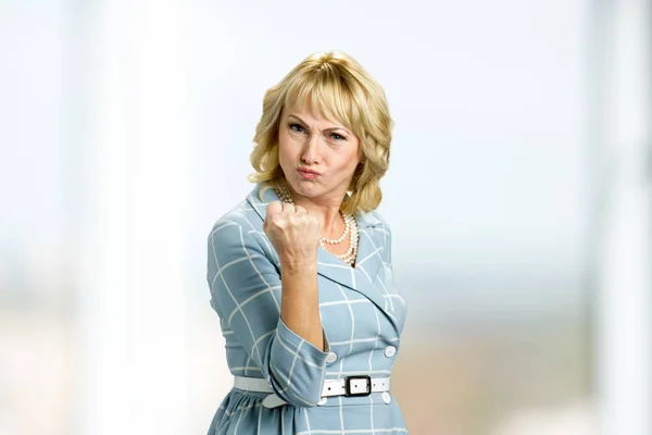 Angry mature woman showing fist.