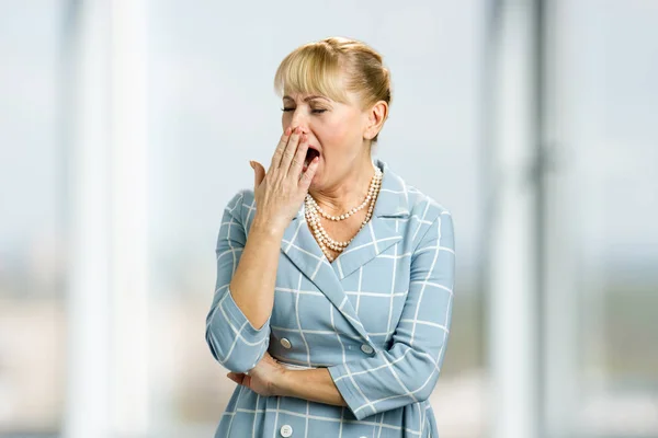 Bocejando mulher madura, fundo borrado . — Fotografia de Stock