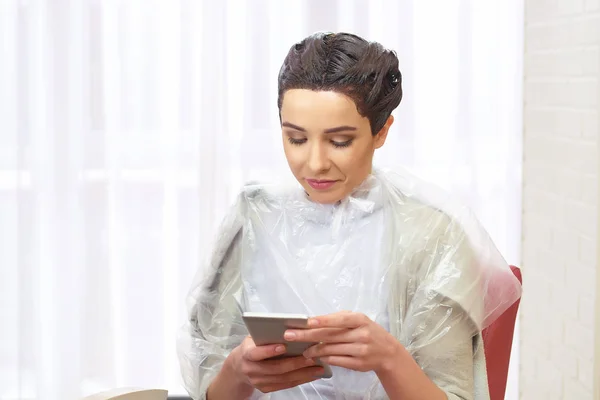 Woman in hair salon, phone.