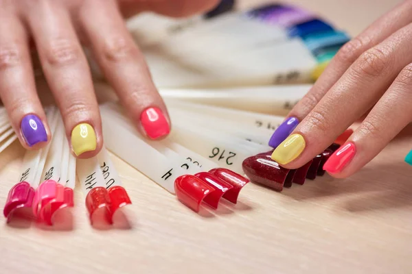 Meisjes vingers met veelkleurige nagels. — Stockfoto