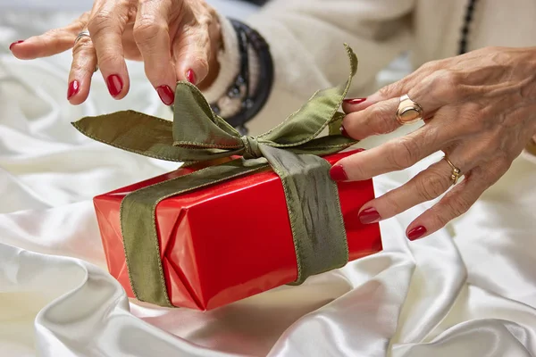 Female hands and red gift box.